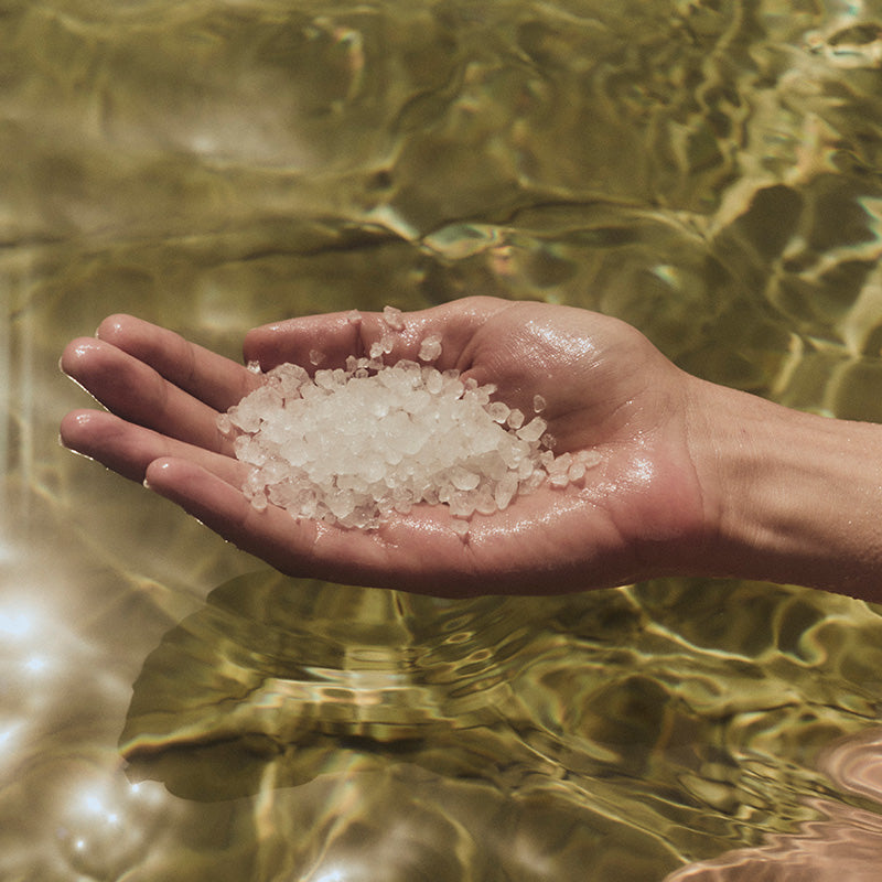 Hand above water with big crystals of salt